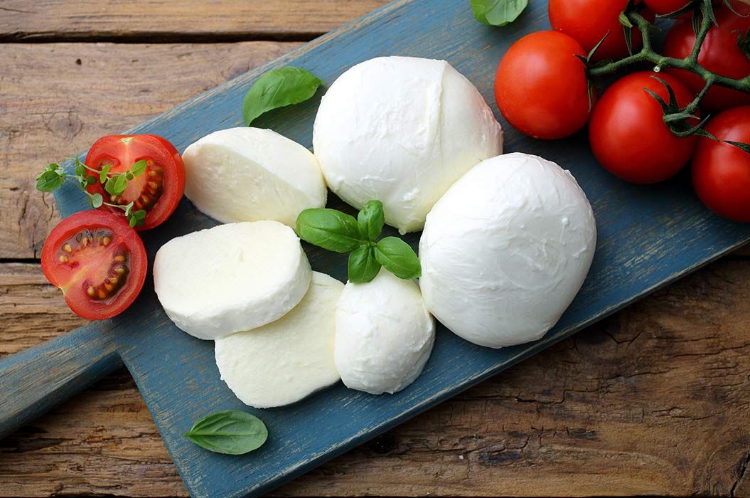 Mozzarella mit Tomaten auf einem Brett angerichtet